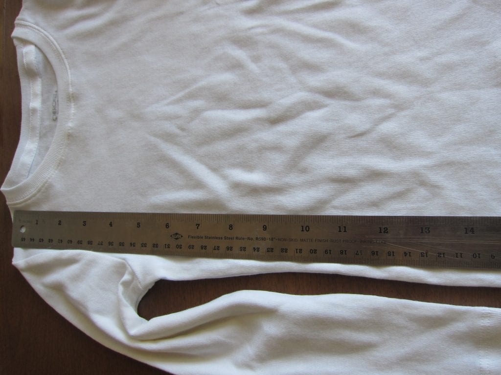 Measure the child from the top of the should to the natural waist and add one inch. Mark this measurement on the shirt.