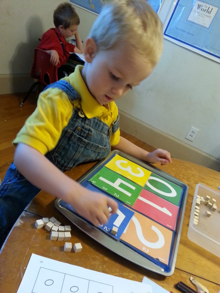 Math tray: Placing the correct number of counters on each number card solidifies the connection between an amount and the numeral representing that amount.